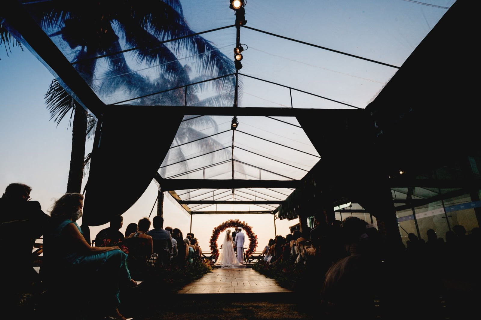 Evening outdoor wedding ceremony with palm trees and guests